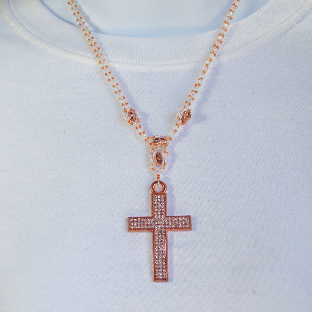 Cross in copper metal designed in fave crystals.  Clear seed bead and Czech Glass beads in Apricot color suing netting stitch for neckwear.  