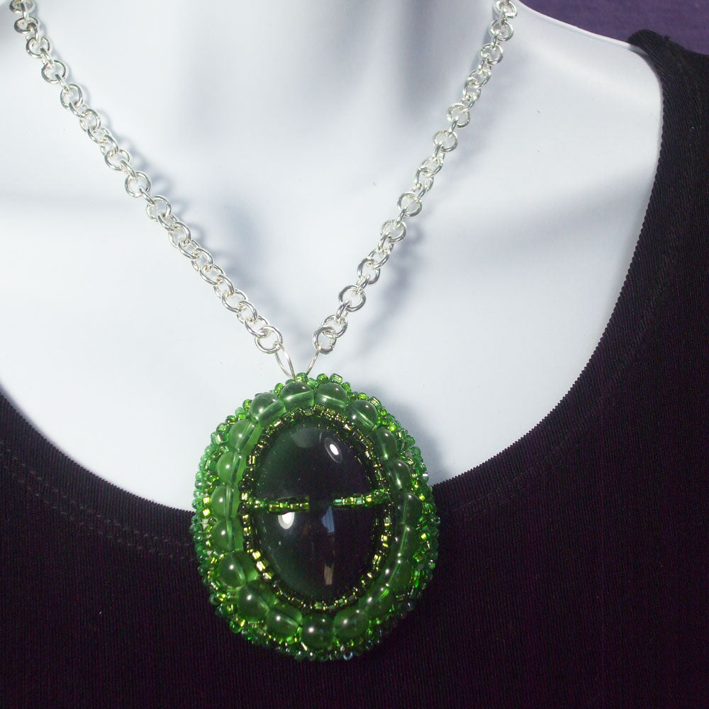 Green button cabochon embellished with green seed bead Bezel.  Silver wire bail and silver link chain neckwear.   