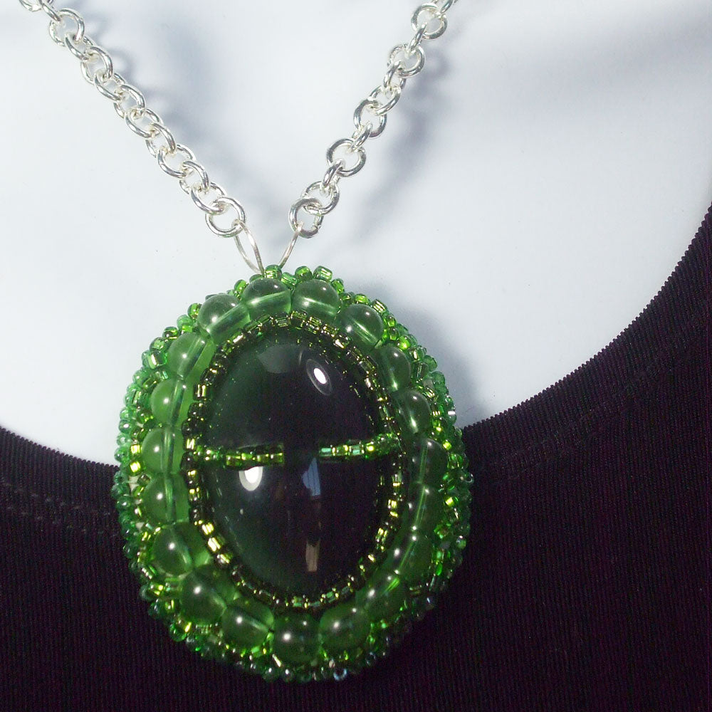 Green button cabochon embellished with green seed bead Bezel.  Silver wire bail and silver link chain neckwear.   