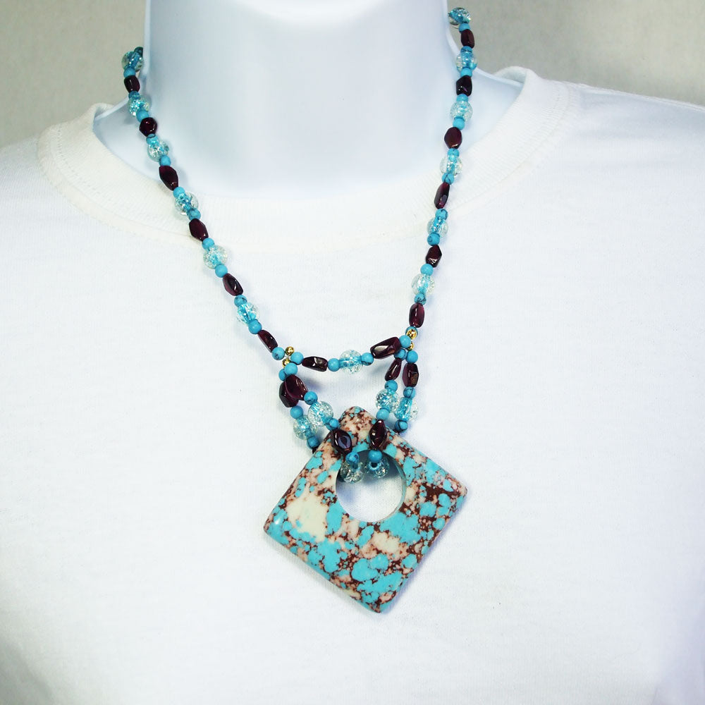 7490-Turquoise and Pyrite mineral square shaped donut pendant. Turquoise and Garnet beads, with crystal accent beads in neckwear.