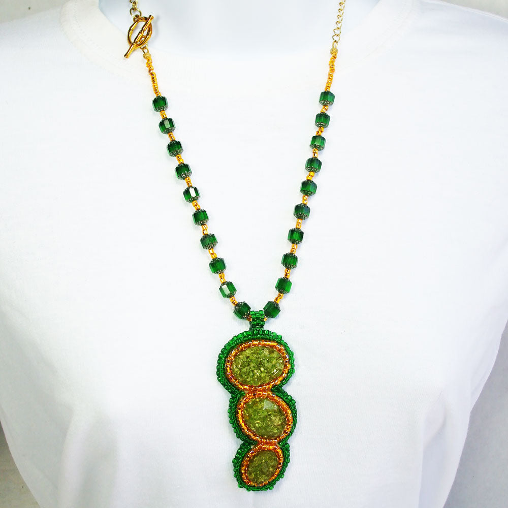 7491-Green crushed glass cabochon, gold and green bezel. Green glass beads with gold seed bead accent for neckwear.